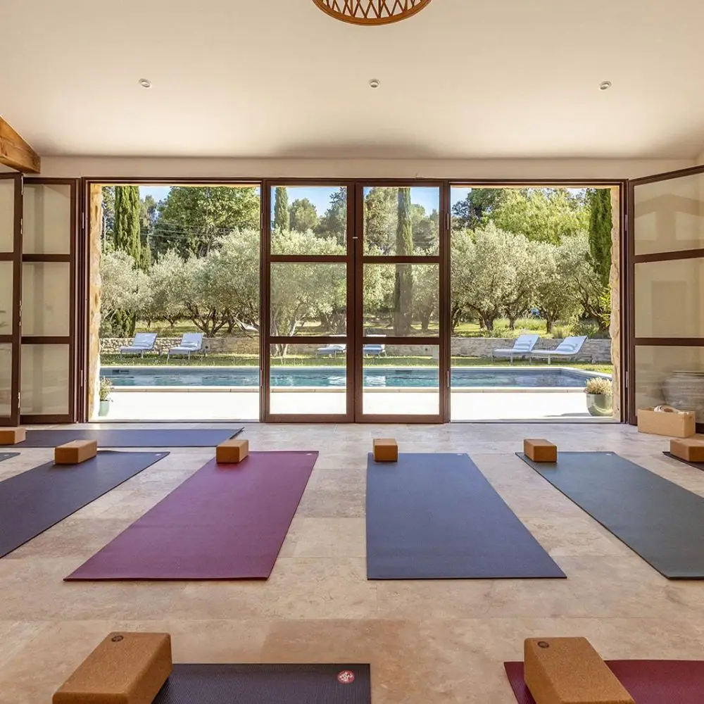 Salle de yoga baignée de lumière, ouverte sur les oliviers et la piscine